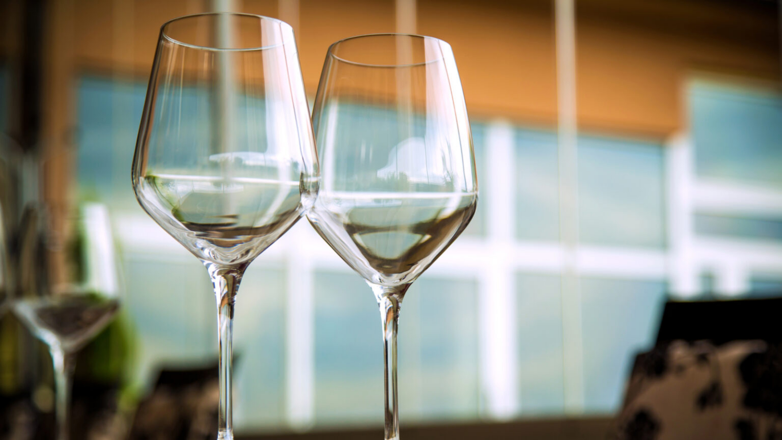 Natural light or daylight shot of modern restaurant table set for a lunch. Shallow focus on wine glass