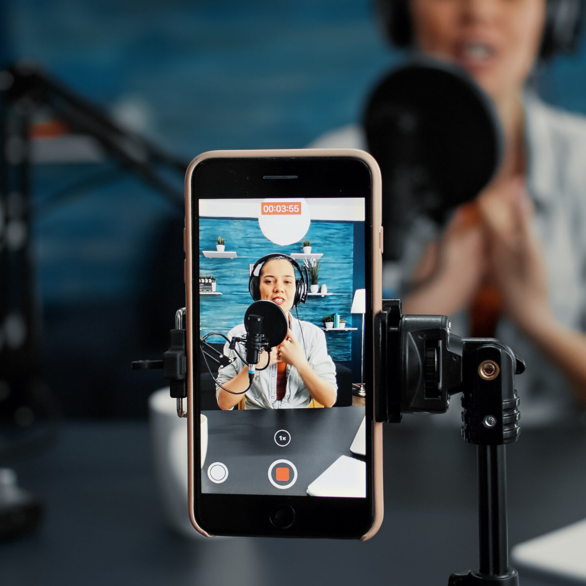 Modern smartphone recording vlogger talking to public while sitting at home studio desk. Famous influencer filming podcast show with touchscreen display device while sitting in living room. Close up
